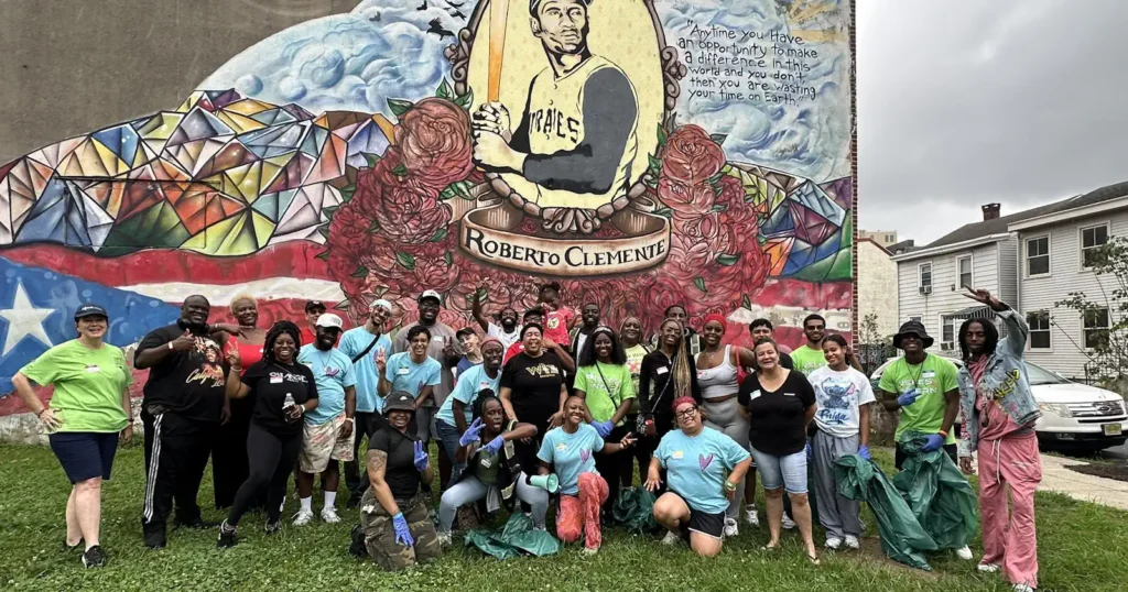 People posing in front of Roberto Clemente mural wall.