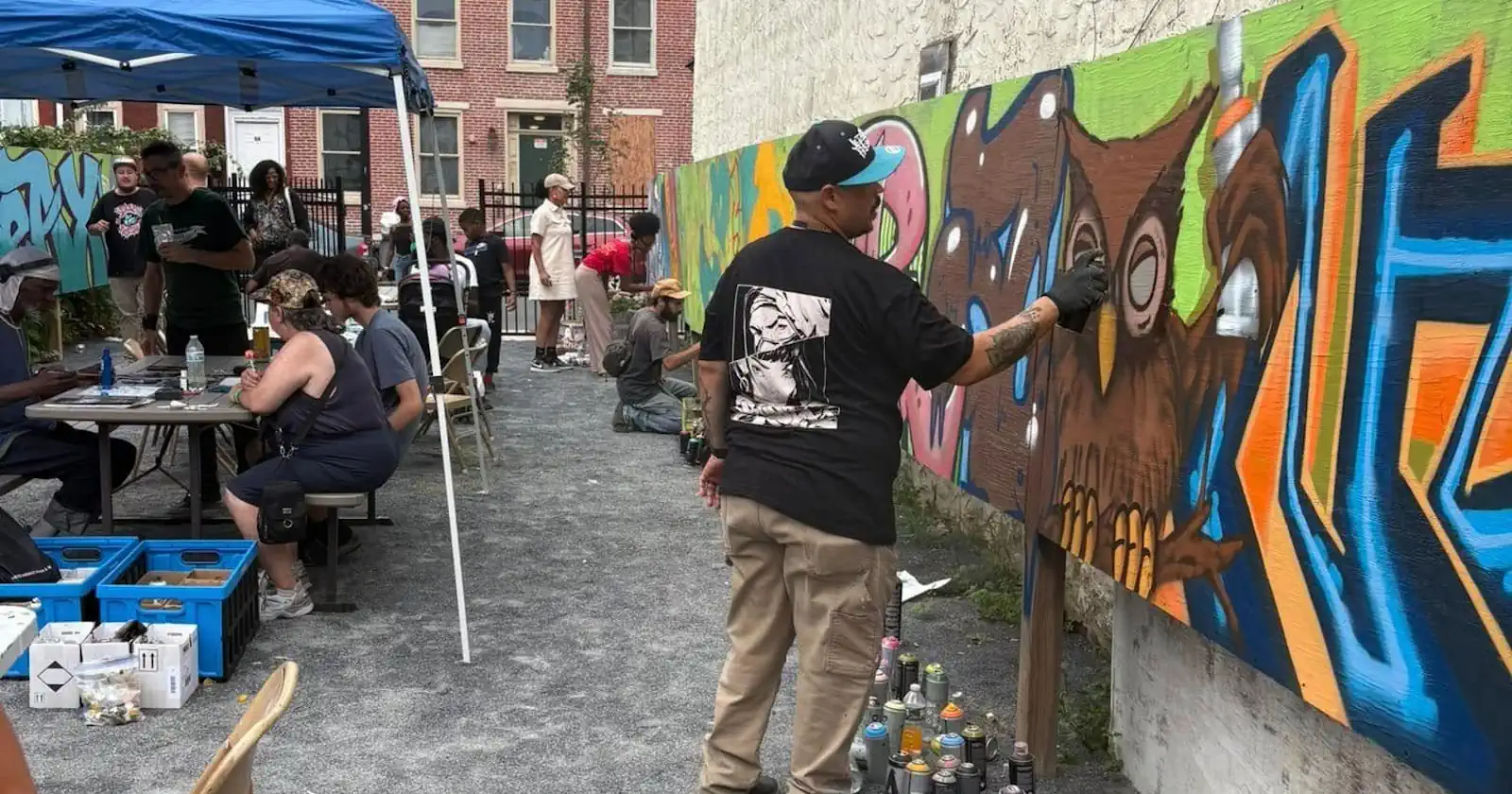 People working on graffiti art wall in an alley way