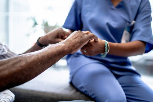 Nurse helping an elderly patient to get up from a seated position