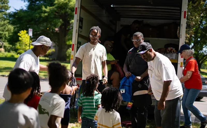 Trenton Community Street Team handing out backpacks to young children